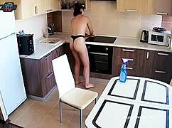 Big tits beauty cleans the kitchen topless, showing off pierced nipples.