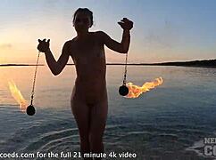 Pretty european girl performs nude fire dancing on usa beach at sunset