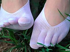 goddess feet in cute white socks on spring grass field