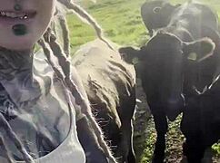 happy hippie chats cows while flashing tattooed body
