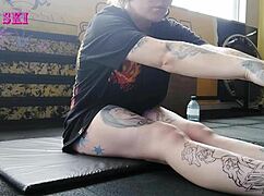 alternative tattooed girl stretches deep at gym