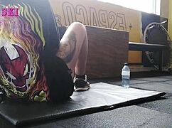 alternative tattooed girl stretches deep at gym