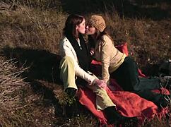 lesbian couple shares a soft kiss outdoors then straps on for heated pussy licking action