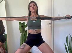 inked babe stretches with rubber bands in sfw yoga workout